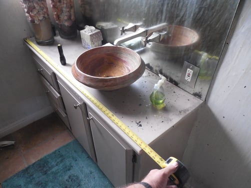 Contractor measuring bathroom vanity damaged in house fire