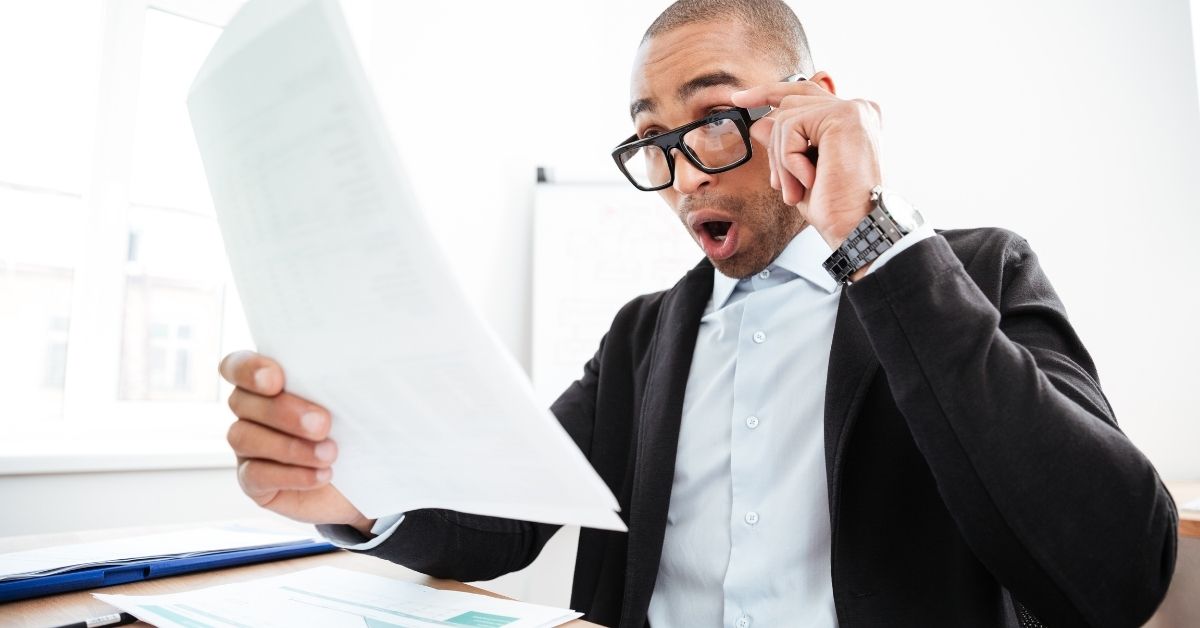 Shocked business man looking at papers holding glasses